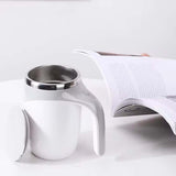 Automatic stirring cup mug with stainless steel interior next to a magazine, perfect for coffee lovers.